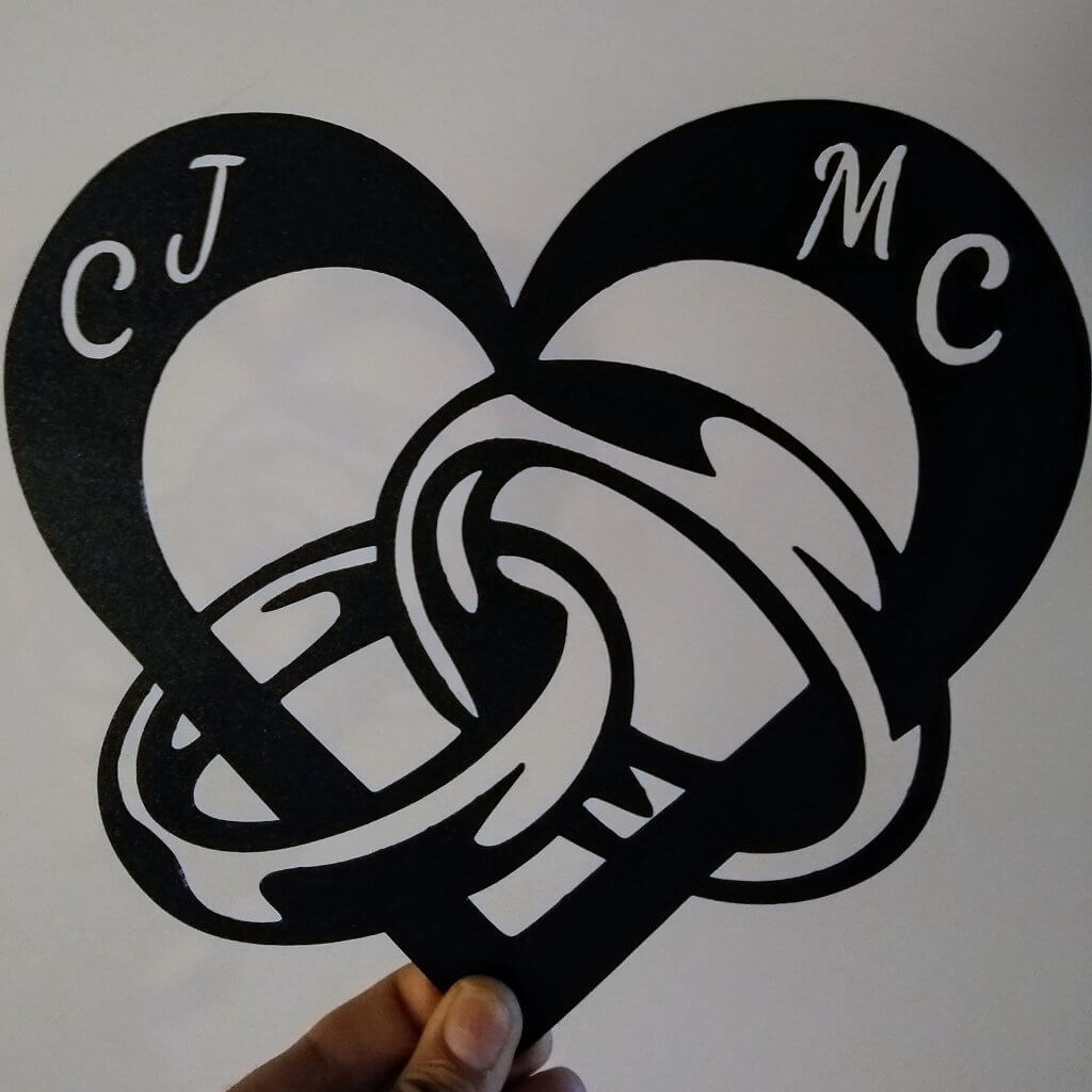 Décoration murale d'un cœur avec les anneaux des mariés et leurs initiales